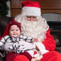 一个婴儿坐在圣诞老人的腿上.